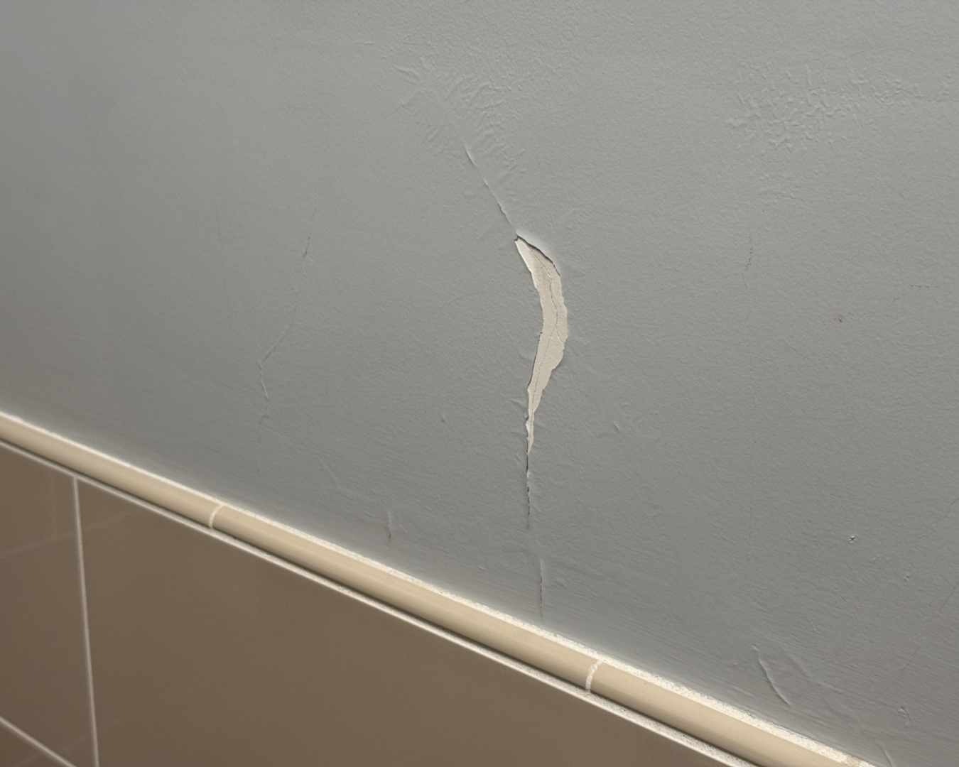 Wall paint peeling above tiles