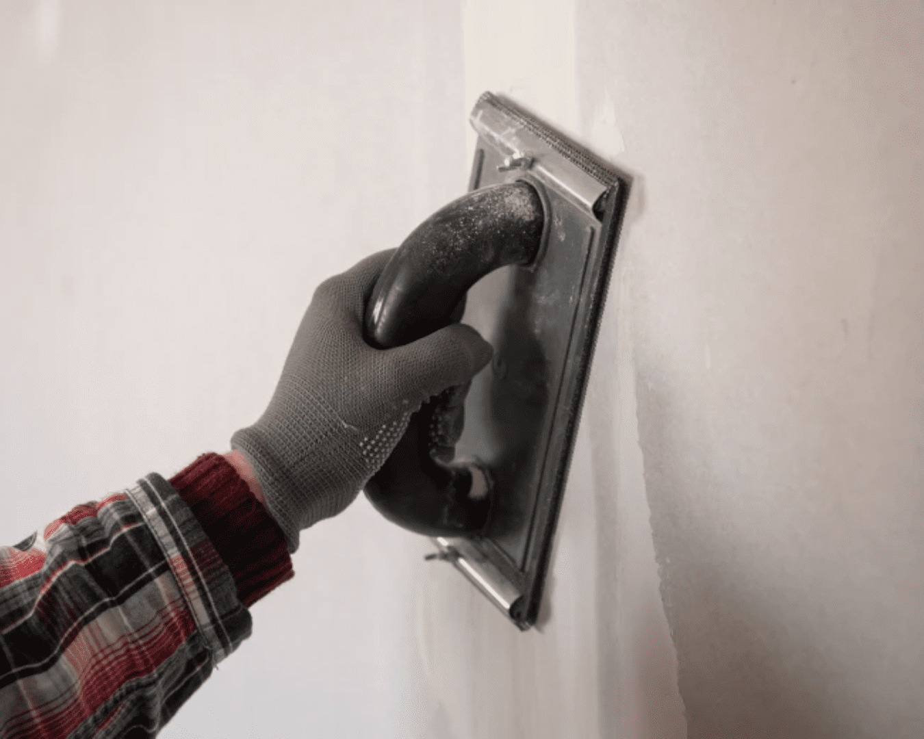 Hand sanding a wall with tool.